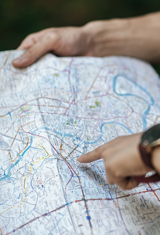Young trekking couple use map while walking on forest trail Close up and selective focus lady finger point on paper map to checking direction while trekking in forest
